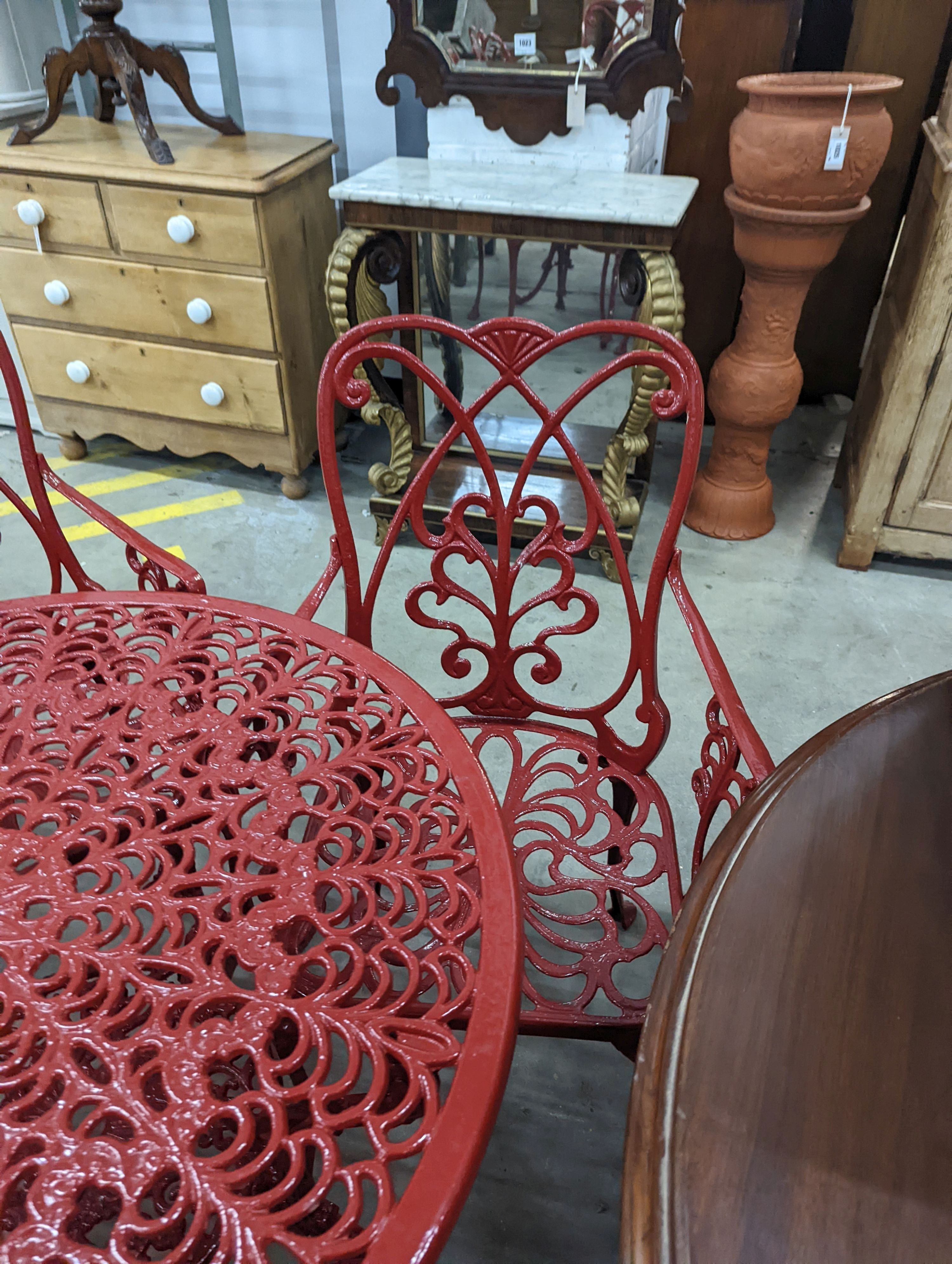 A circular red painted aluminium garden table, diameter 86cm, height 67cm together with four matching chairs